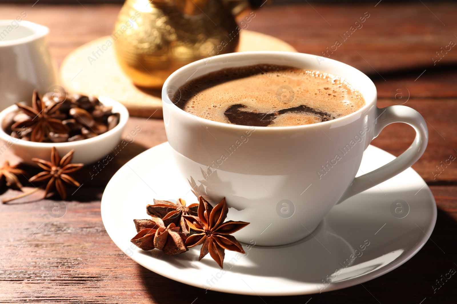 Photo of Cup of aromatic hot coffee with anise stars on wooden table