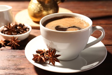 Cup of aromatic hot coffee with anise stars on wooden table