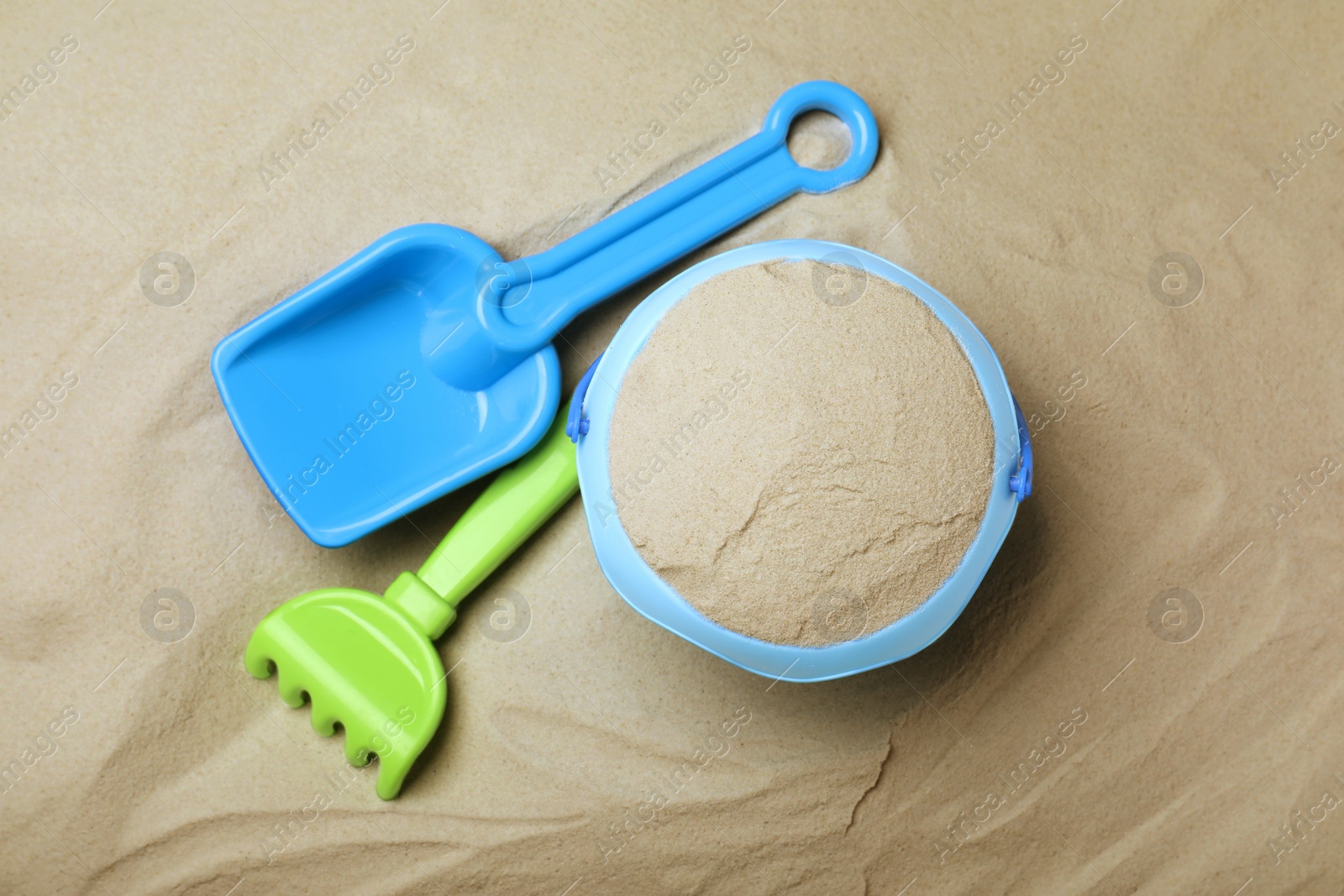 Photo of Plastic toy set with shovel on sand, flat lay