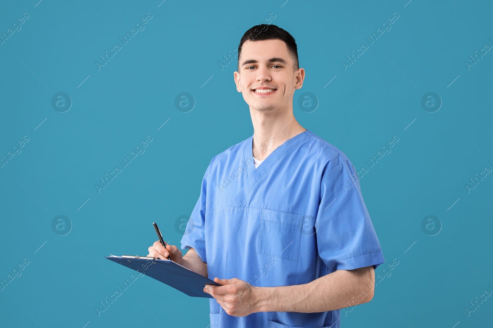 Photo of Portrait of smiling medical assistant with clipboard on light blue background