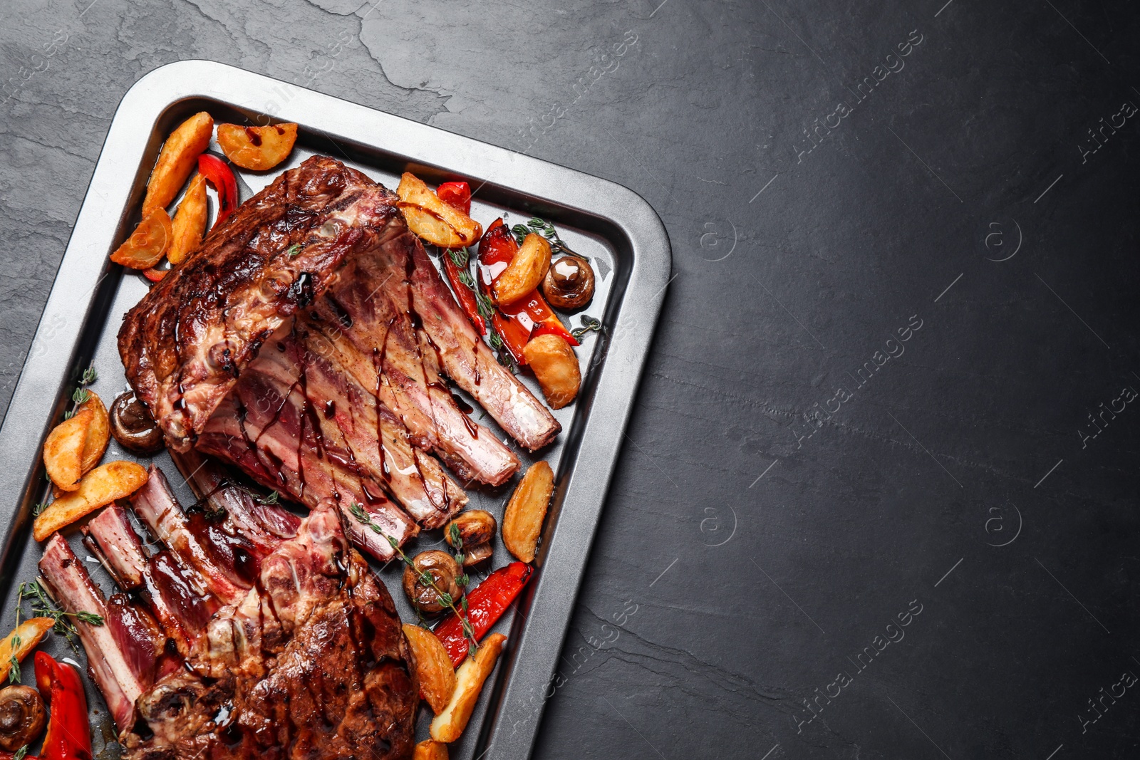 Photo of Delicious roasted ribs with garnish, top view. Space for text