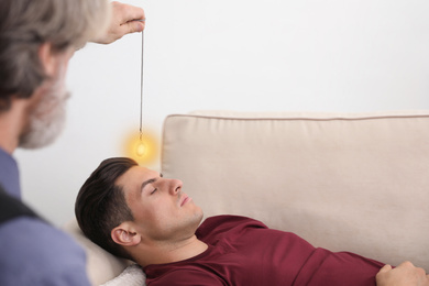 Psychotherapist using pendulum during hypnotherapy   session in office