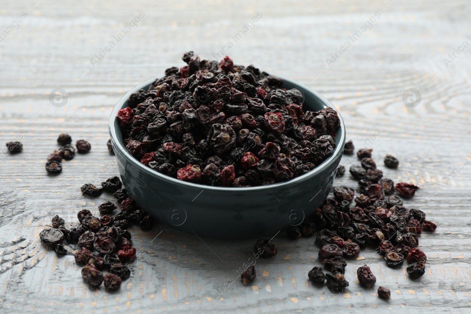 Photo of Dried black currants and bowl on grey wooden table