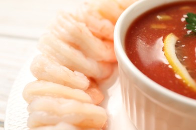 Tasty boiled shrimps with cocktail sauce and lemon on plate, closeup