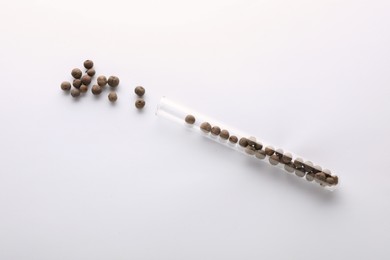 Photo of Glass tube with allspice peppercorns on white background, top view