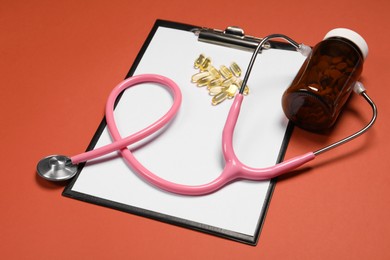 Stethoscope, pills and clipboard on crimson background. Medical tool