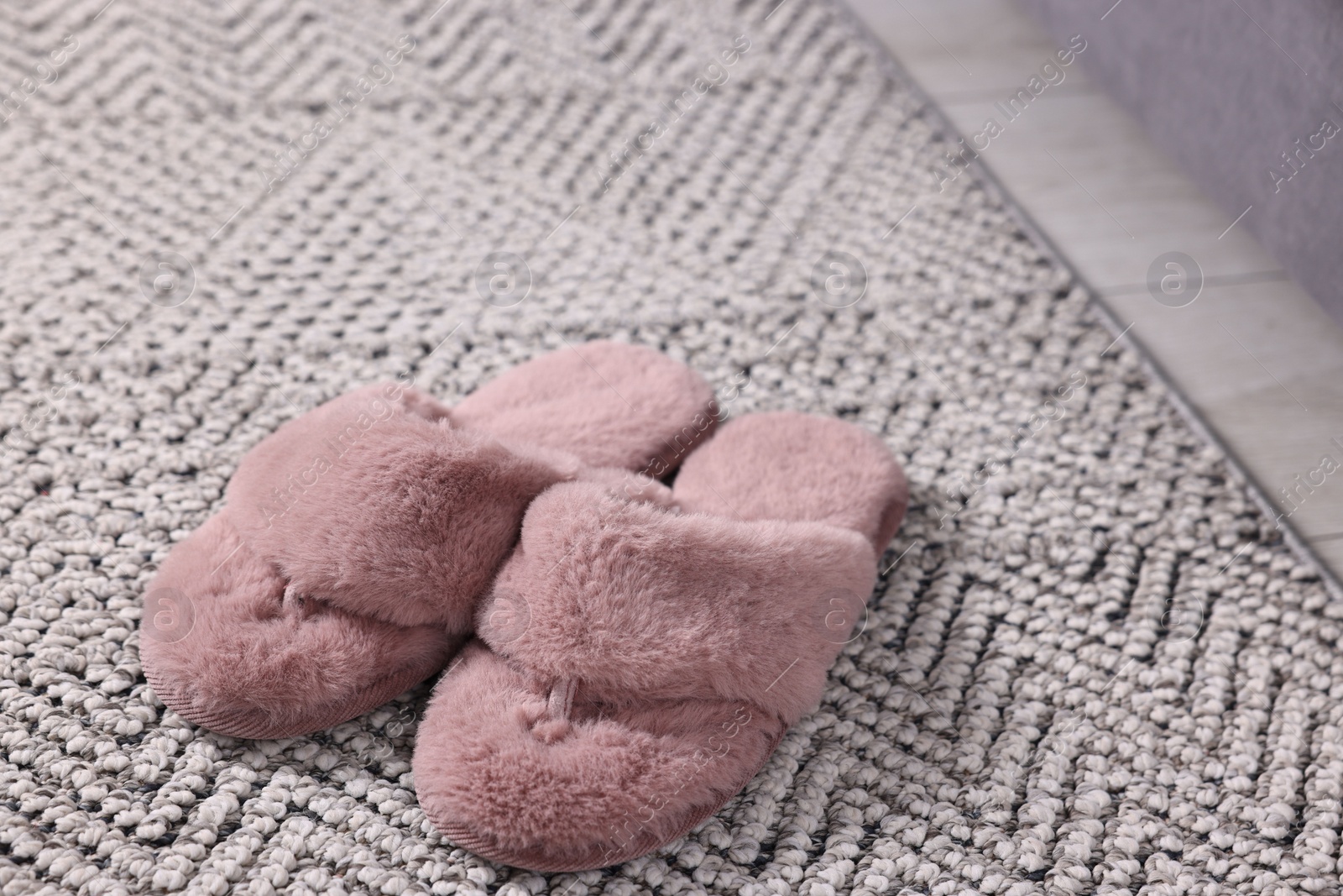 Photo of Pink soft slippers on carpet at home, closeup