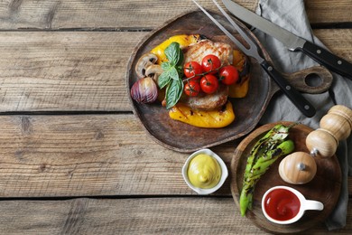 Photo of Delicious grilled meat and vegetables served with sauces on wooden table, flat lay. Space for text