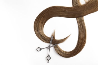 Beautiful strands of brown hair and scissors on white background, top view. Hairdresser service