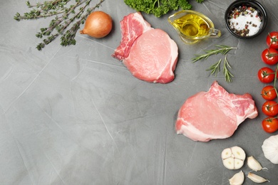 Photo of Flat lay composition with raw steaks, products and space for text on gray background. Fresh meat