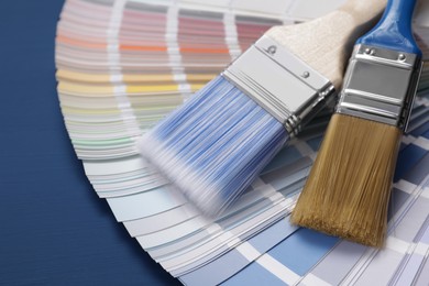 Photo of Paint brushes and palette on blue wooden table, closeup