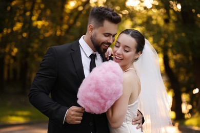Happy newlywed couple with cotton candy in park