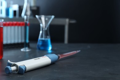 Laboratory analysis. Micropipette with liquid on black table, closeup. Space for text