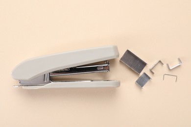 Photo of Stapler with staples on beige background, flat lay