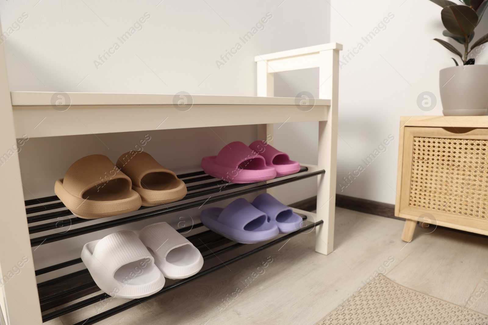 Photo of Storage bench with pairs of rubber slippers in room