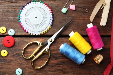 Threads and other sewing supplies on wooden table, flat lay
