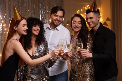 Photo of Happy friends clinking glasses of sparkling wine at birthday party indoors