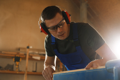 Photo of Professional carpenter working with wood in shop