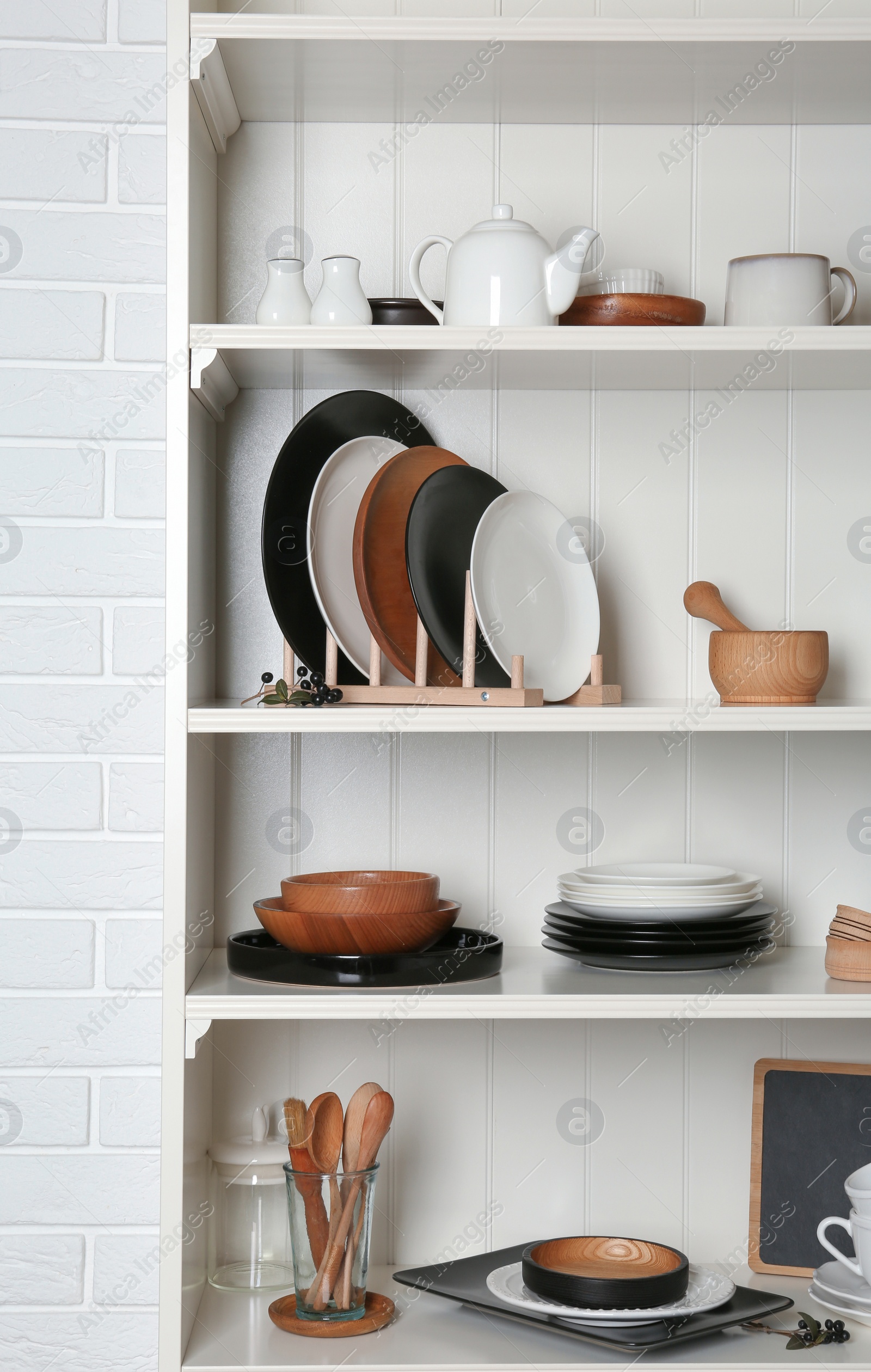 Photo of White shelving unit with set of dishware near brick wall