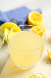 Photo of Freshly squeezed lemon juice in glass on table, closeup