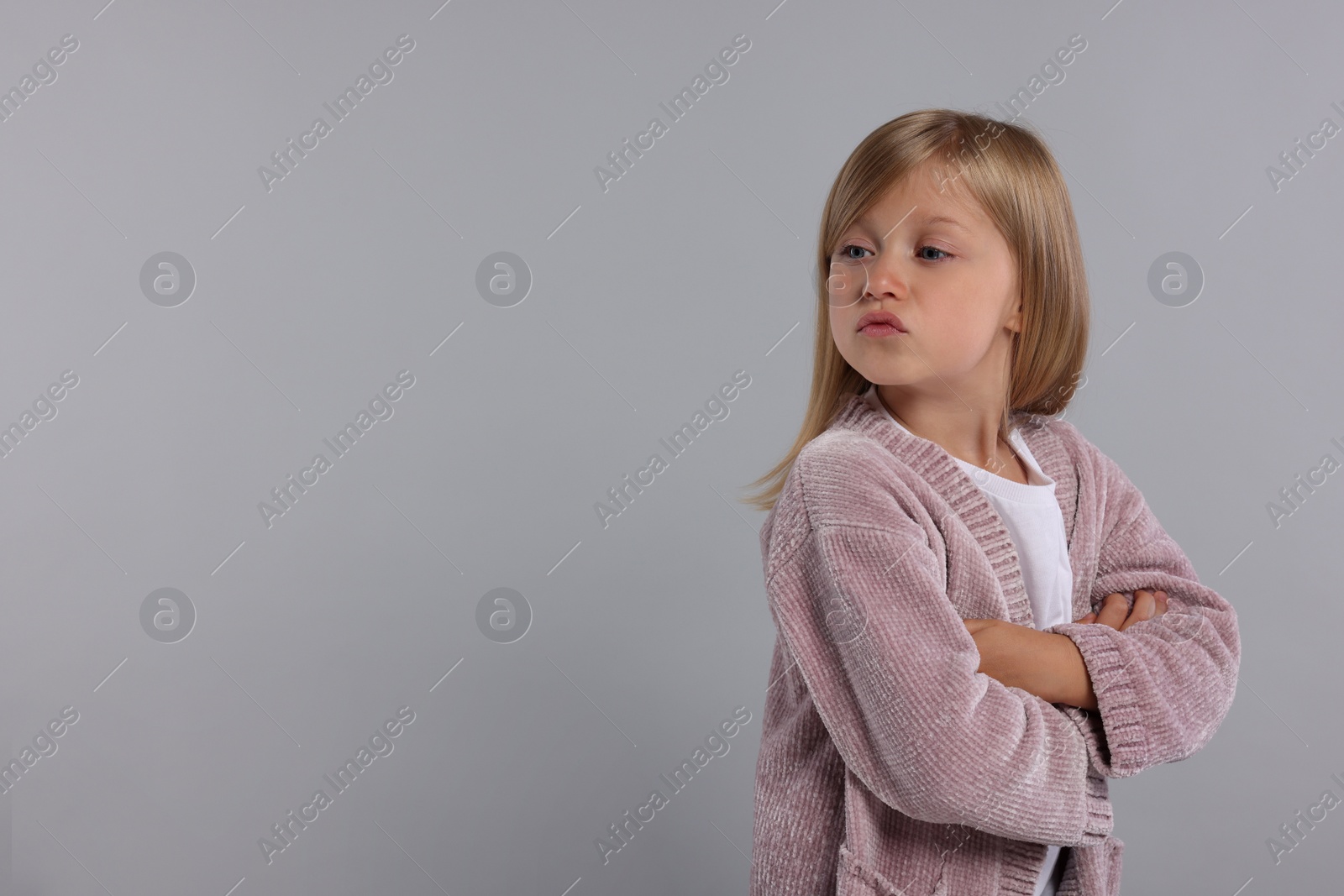 Photo of Resentful girl with crossed arms on grey background. Space for text