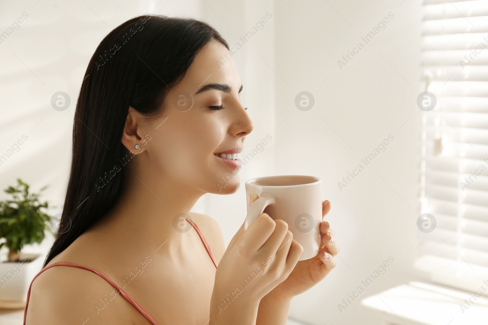 Photo of Woman with cup of tea in bedroom. Lazy morning