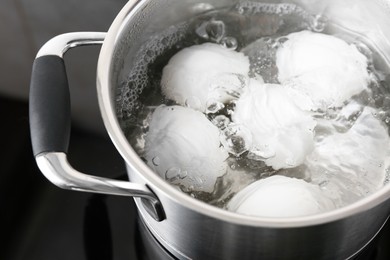Photo of Chicken eggs boiling in pot on electric stove, closeup