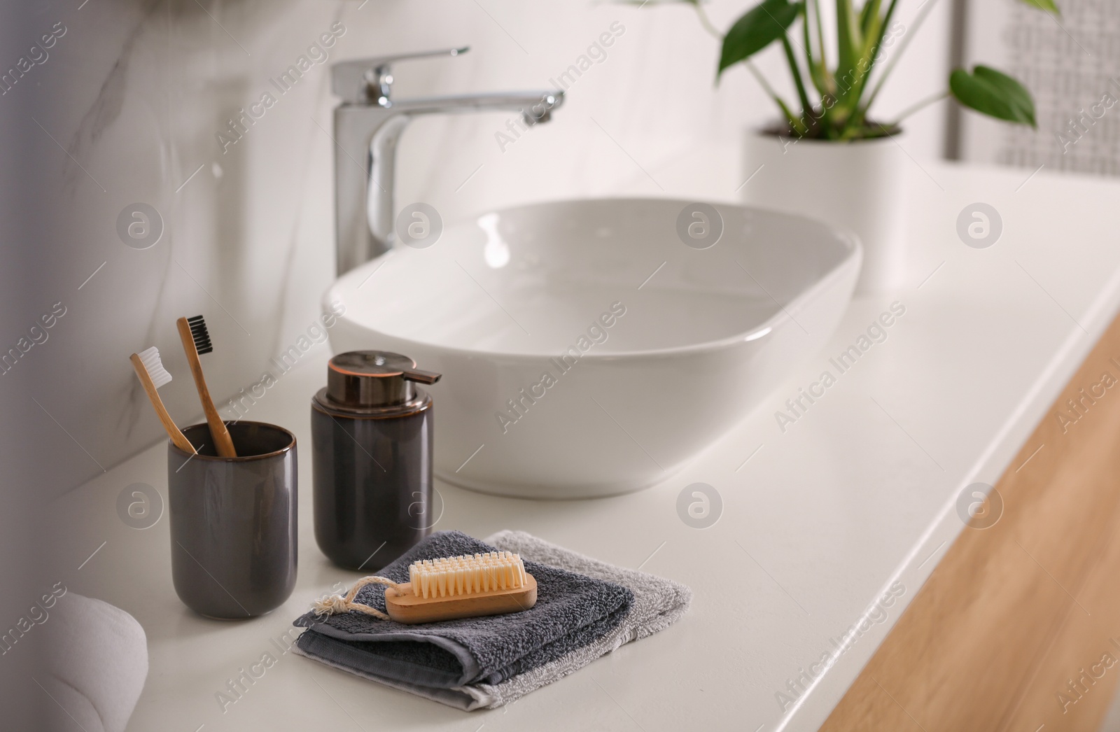 Photo of Toiletries and stylish vessel sink on light countertop in modern bathroom