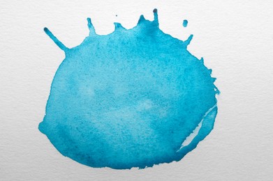 Photo of Blot of light blue watercolor paint on white paper, top view