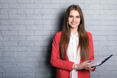 Photo of Beautiful real estate agent with clipboard on brick wall background