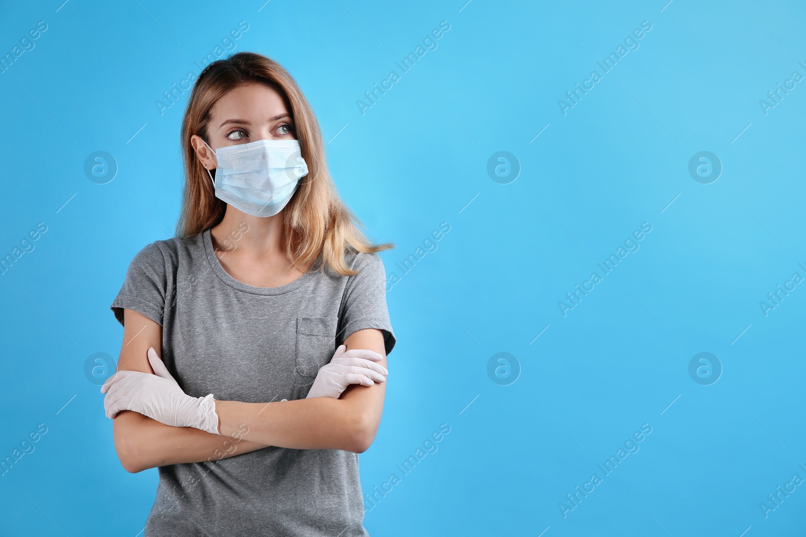 Photo of Young woman in medical gloves and protective mask on light blue background. Space for text