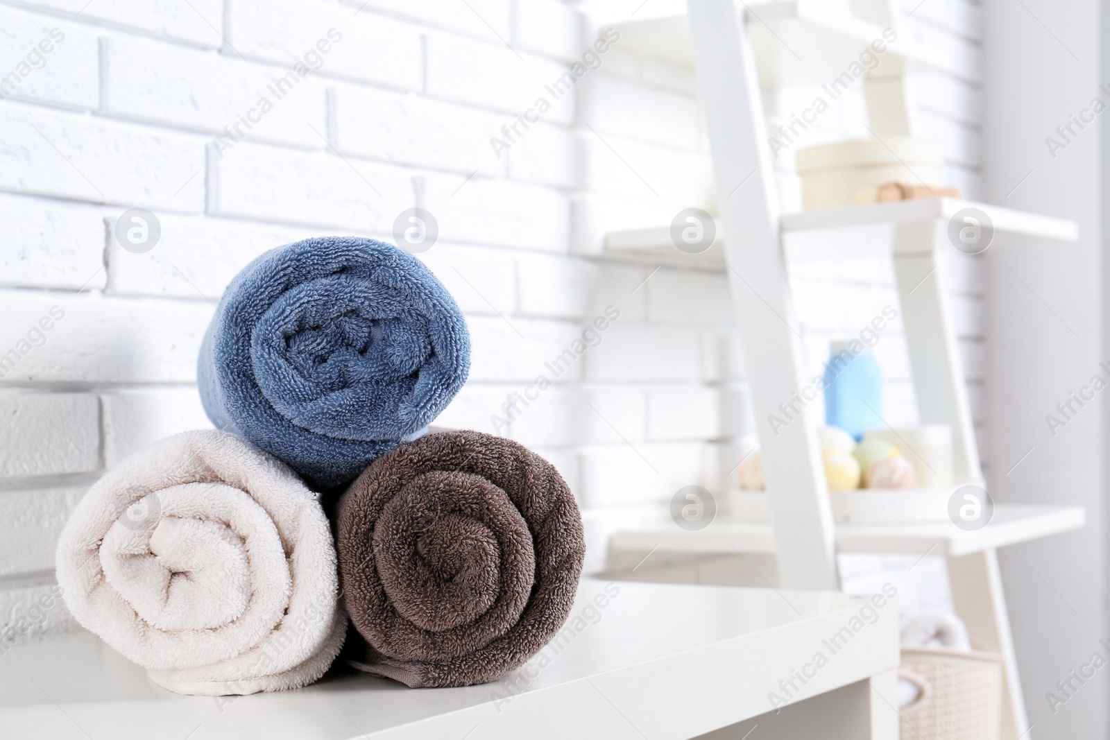 Photo of Rolled fresh towels on table in bathroom. Space for text