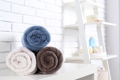 Photo of Rolled fresh towels on table in bathroom. Space for text