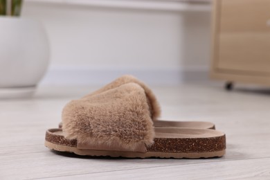 Photo of Soft slippers on light wooden floor indoors, closeup