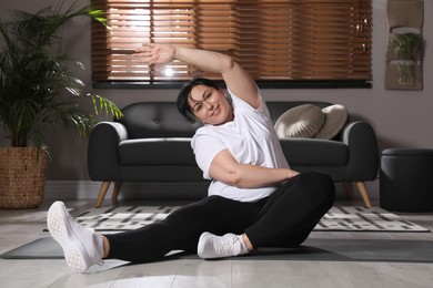 Overweight mature woman doing exercise at home