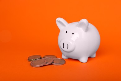 Photo of Ceramic piggy bank and coins on orange background. Financial savings