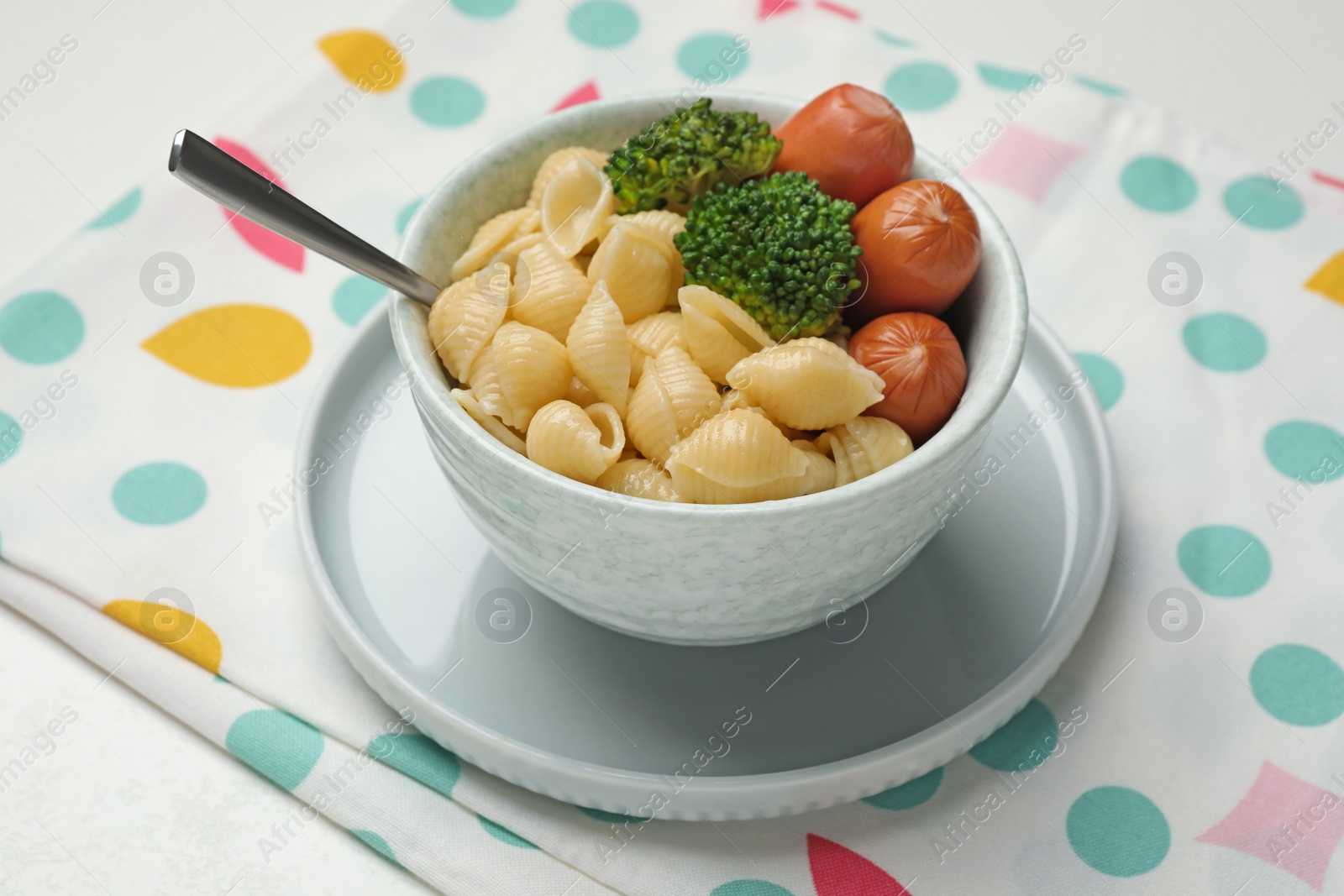 Photo of Bowl with tasty pasta, sausages and broccoli on table