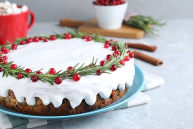 Traditional Christmas cake decorated with rosemary and cranberries on light grey marble table, closeup