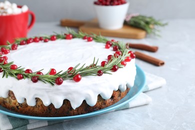 Photo of Traditional Christmas cake decorated with rosemary and cranberries on light grey marble table, closeup