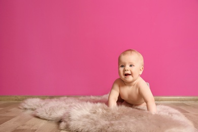 Photo of Cute little baby on fluffy rug near color wall