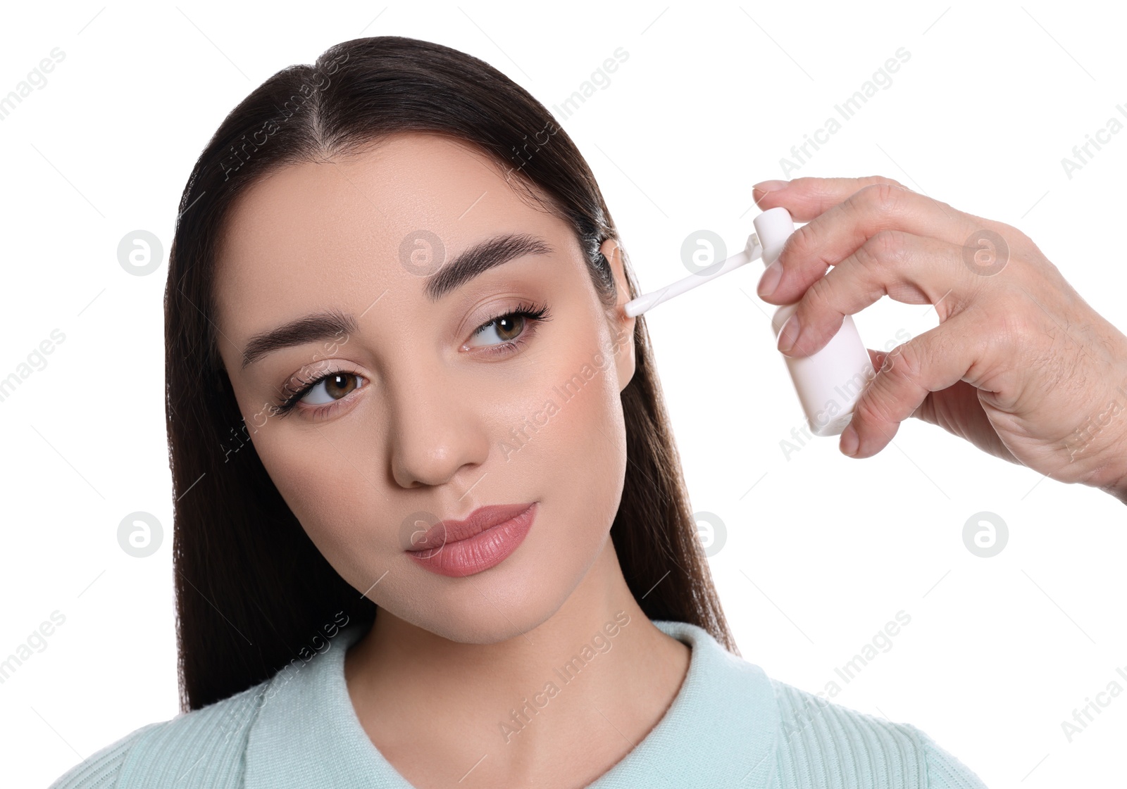 Photo of Doctor spraying medication into woman's ear on white background