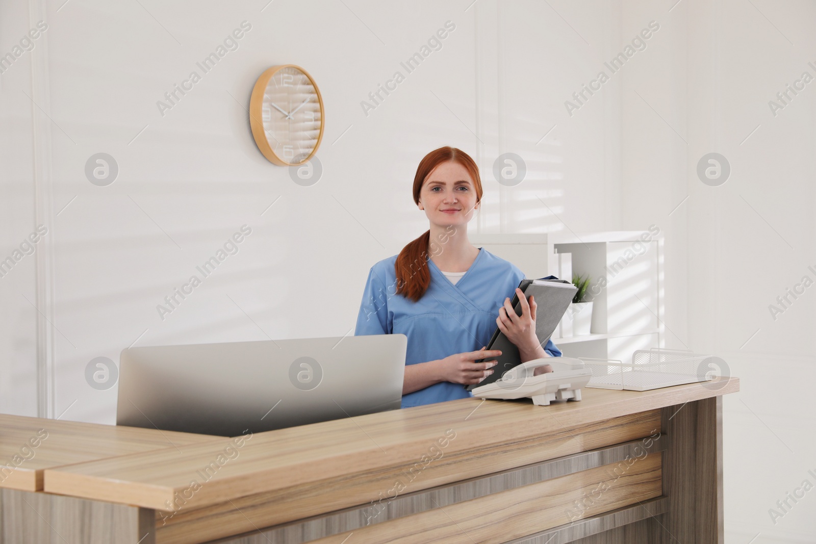 Photo of Receptionist with document cases at countertop in hospital