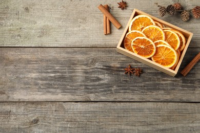 Crate of dry orange slices, cinnamon sticks and anise stars on wooden table, flat lay. Space for text