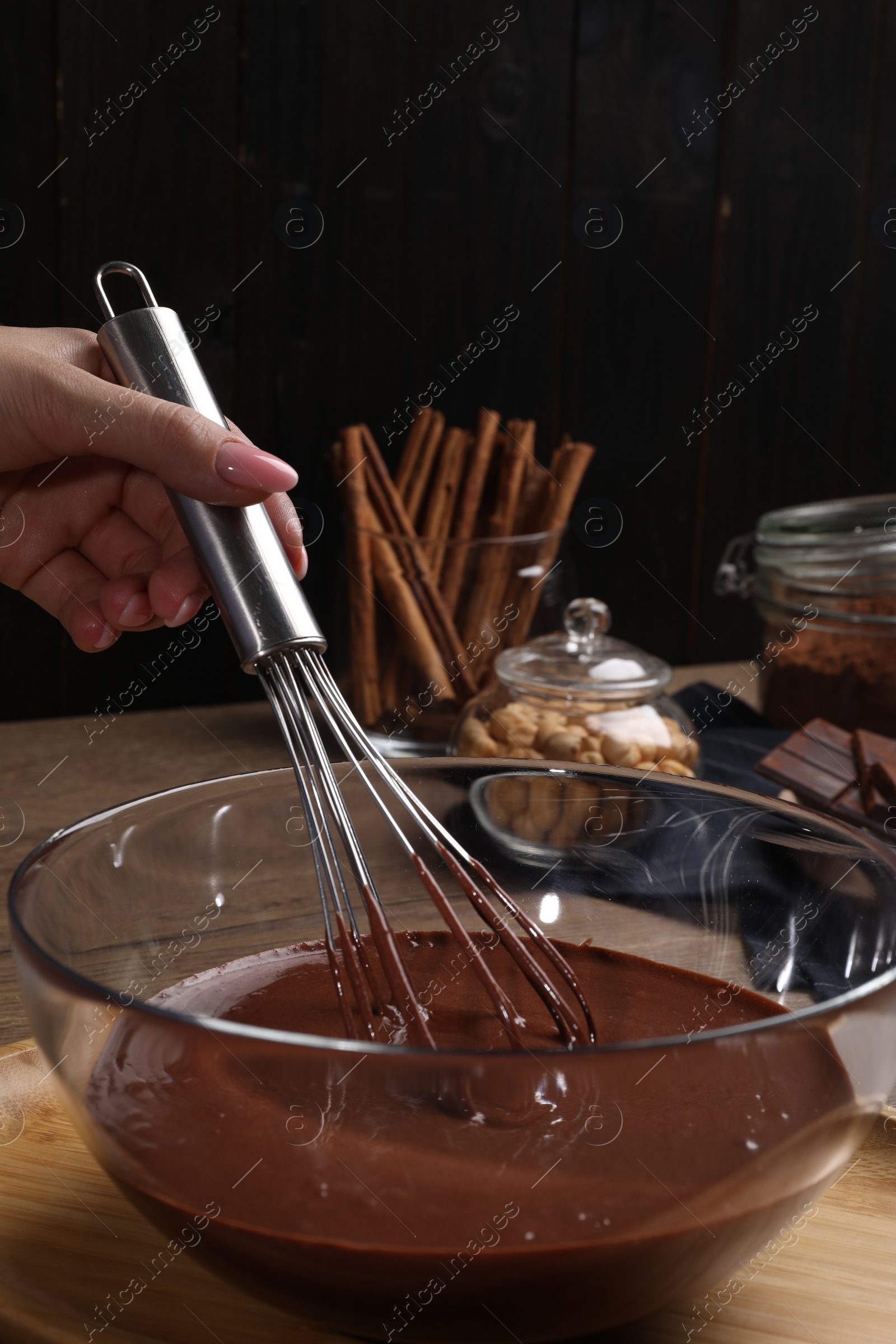 Photo of Woman mixing delicious chocolate cream with whisk at table, closeup