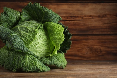 Photo of Fresh ripe savoy cabbage on wooden table, space for text
