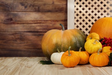 Photo of Happy Thanksgiving day. Pumpkins and berries on wooden table. Space for text