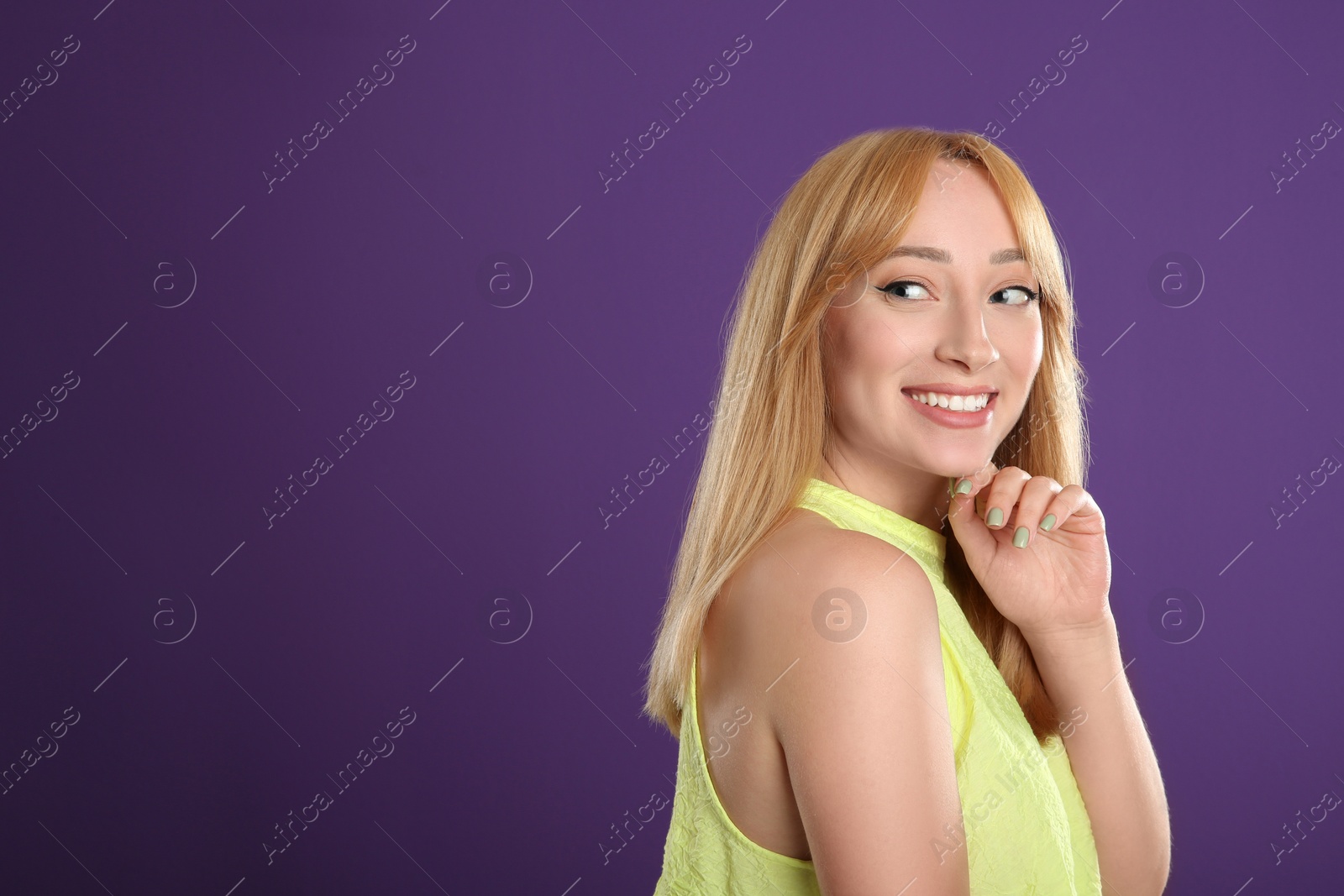 Photo of Beautiful young woman with blonde hair on purple background. Space for text