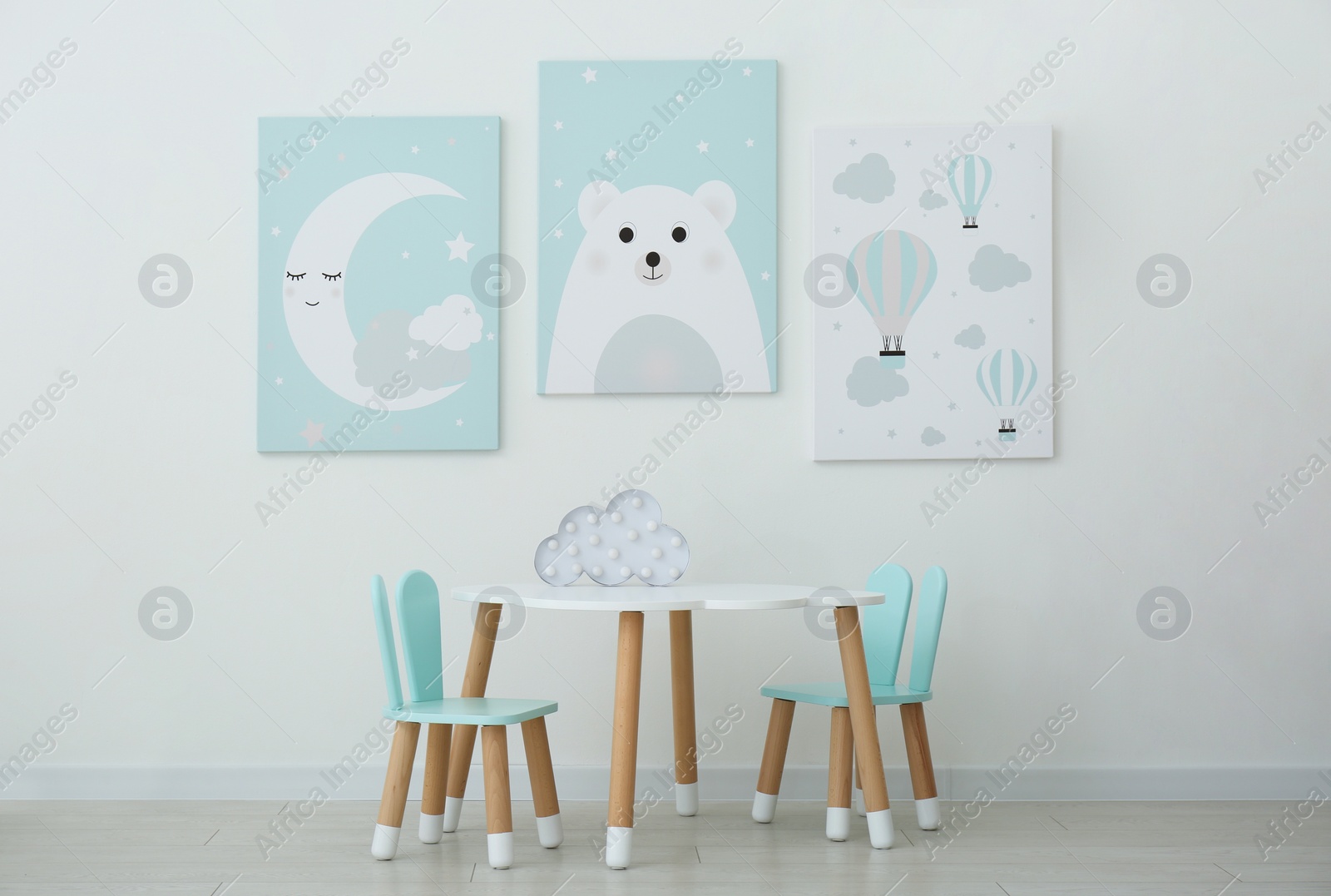 Photo of Adorable wall art, table and chairs with bunny ears in children's room interior