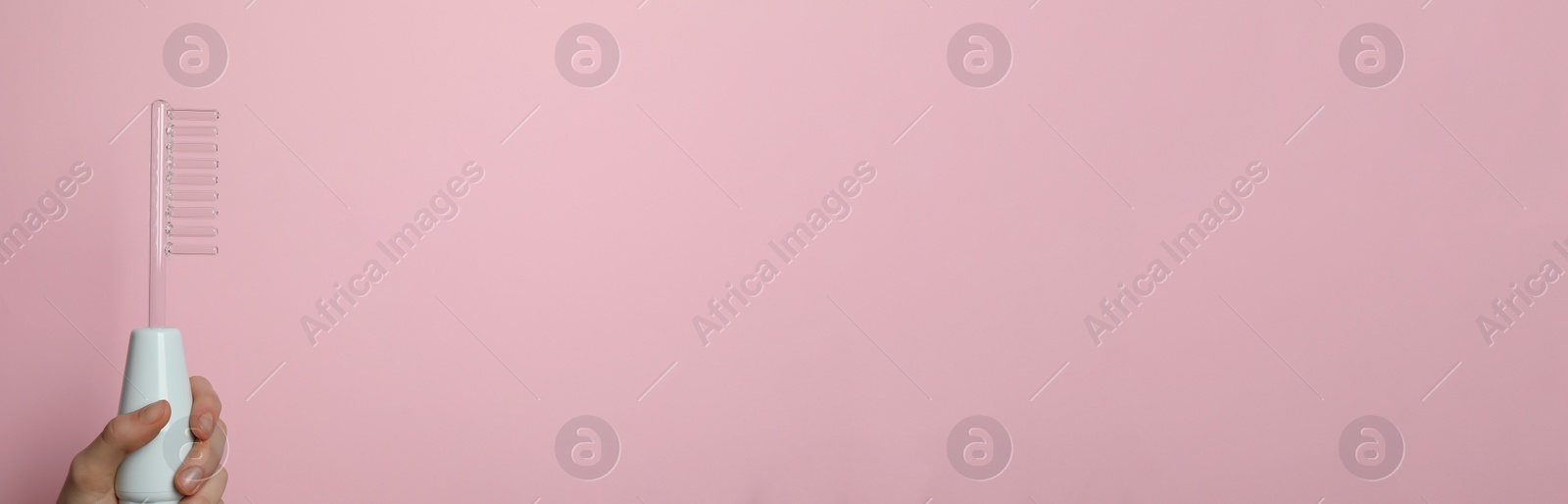 Image of Woman with high frequency darsonval device on pink background, closeup. Banner design with space for text