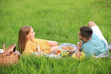 Photo of Happy young couple having picnic on green grass in park